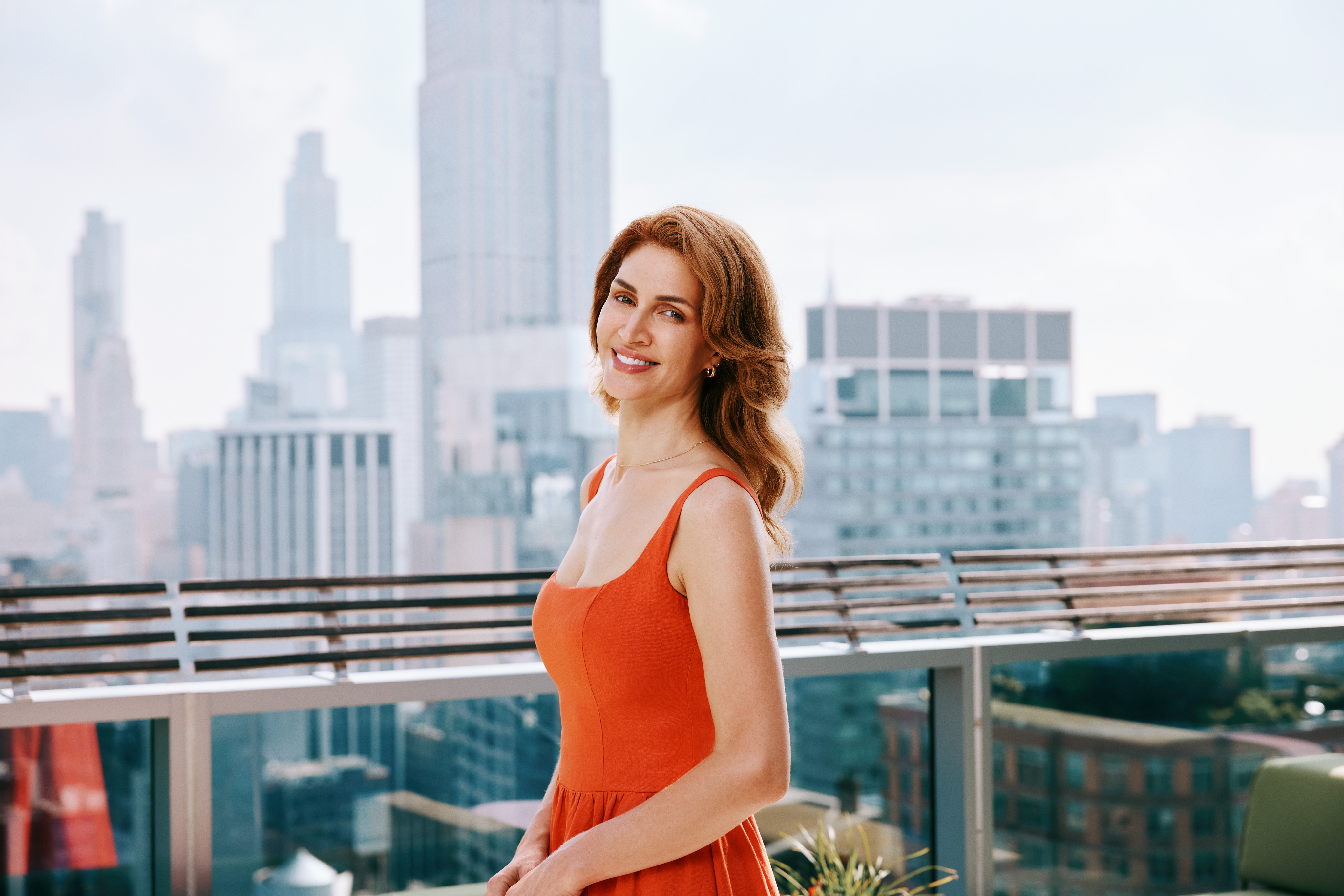 Sculpt & Lift patient wearing an orange dress on a rooftop